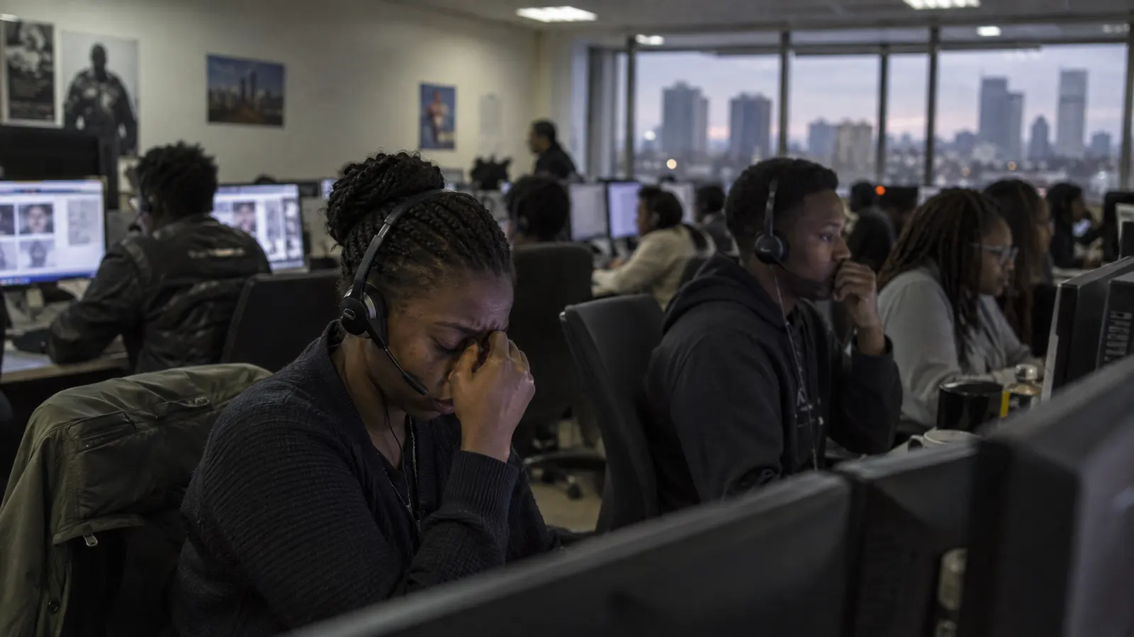 Content moderators in a dim office in Nairobi reviewing disturbing material on screens — illustrating the hidden human labour behind AI
